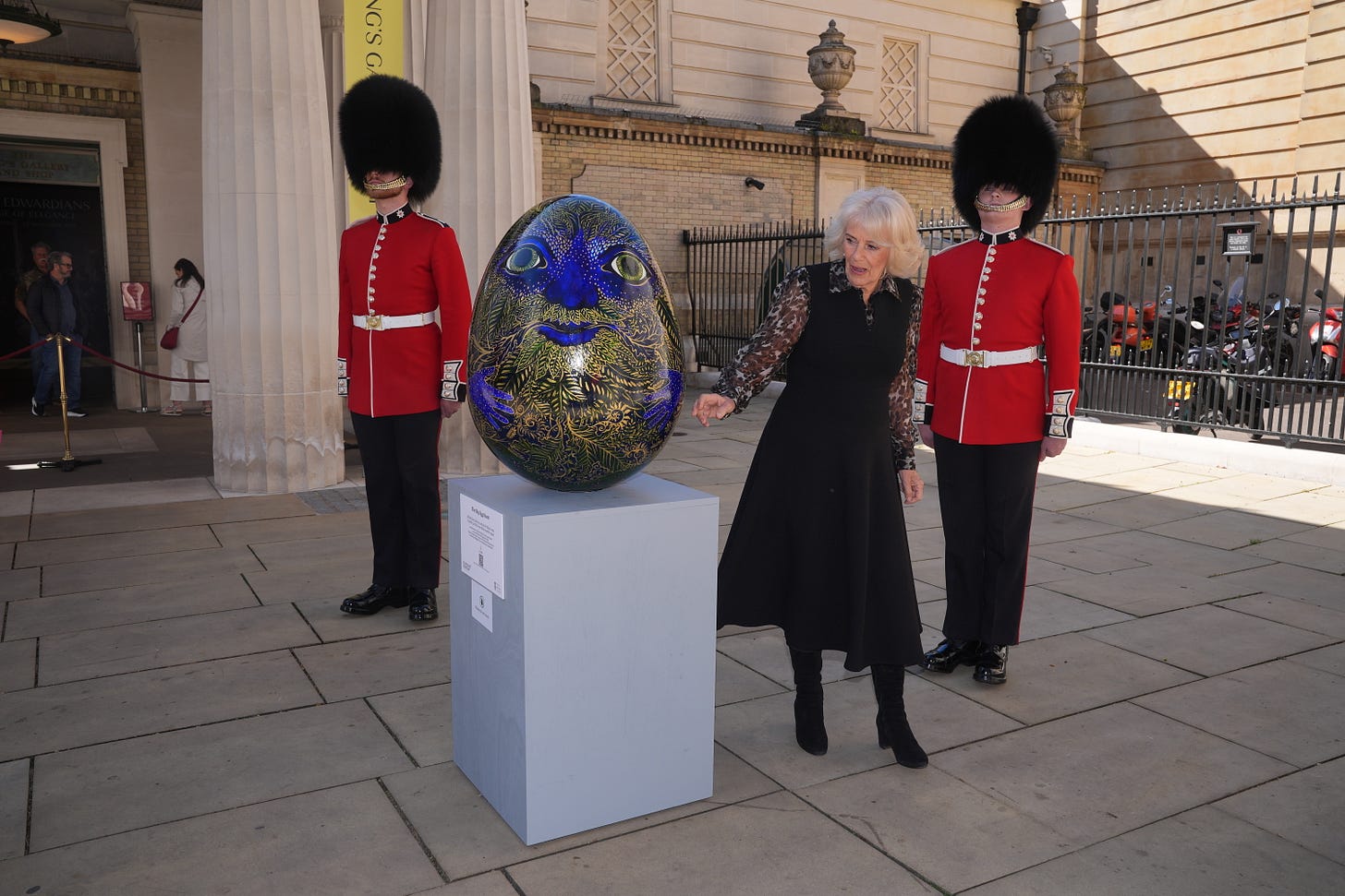 Queen Camilla examines a big blue egg