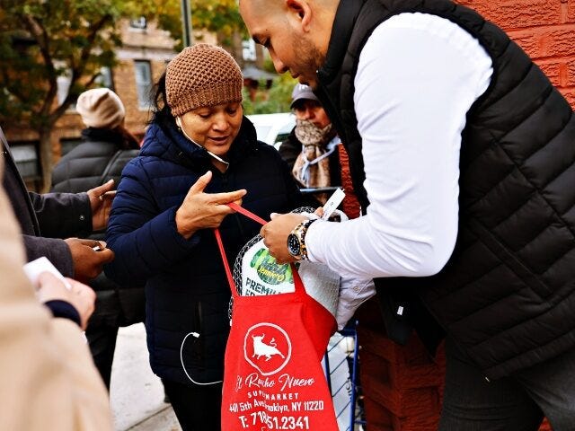 NEW YORK, NEW YORK - NOVEMBER 21: Assemblyman Juan Ardila places a frozen turkey in a bag during a giveaway at Green Valley of Sunnyside Market Place on November 21, 2023 in the Sunnyside neighborhood of Queens borough New York City. The Thanksgiving turkey giveaway was sponsored by the office …