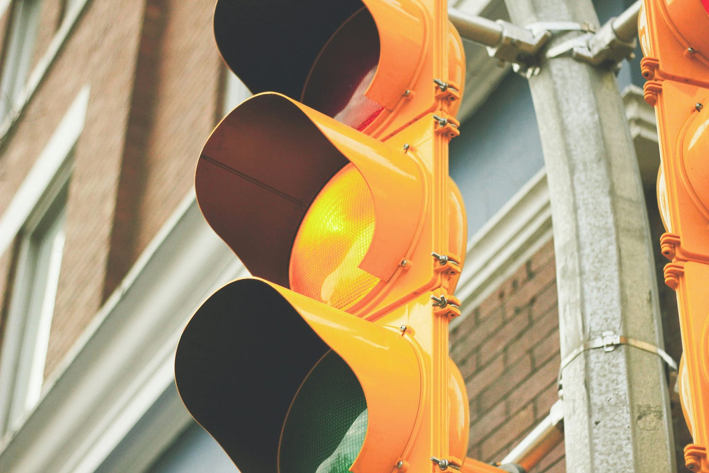 Closeup shot of a yellow traffic light, with the yellow center light on.