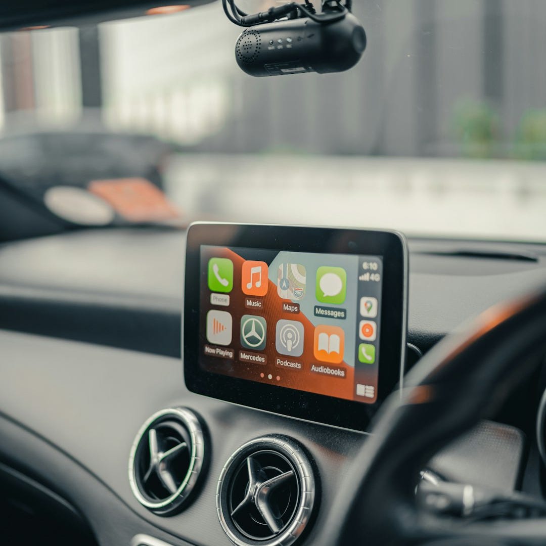 A black iPhone 4 on a car dashboard.