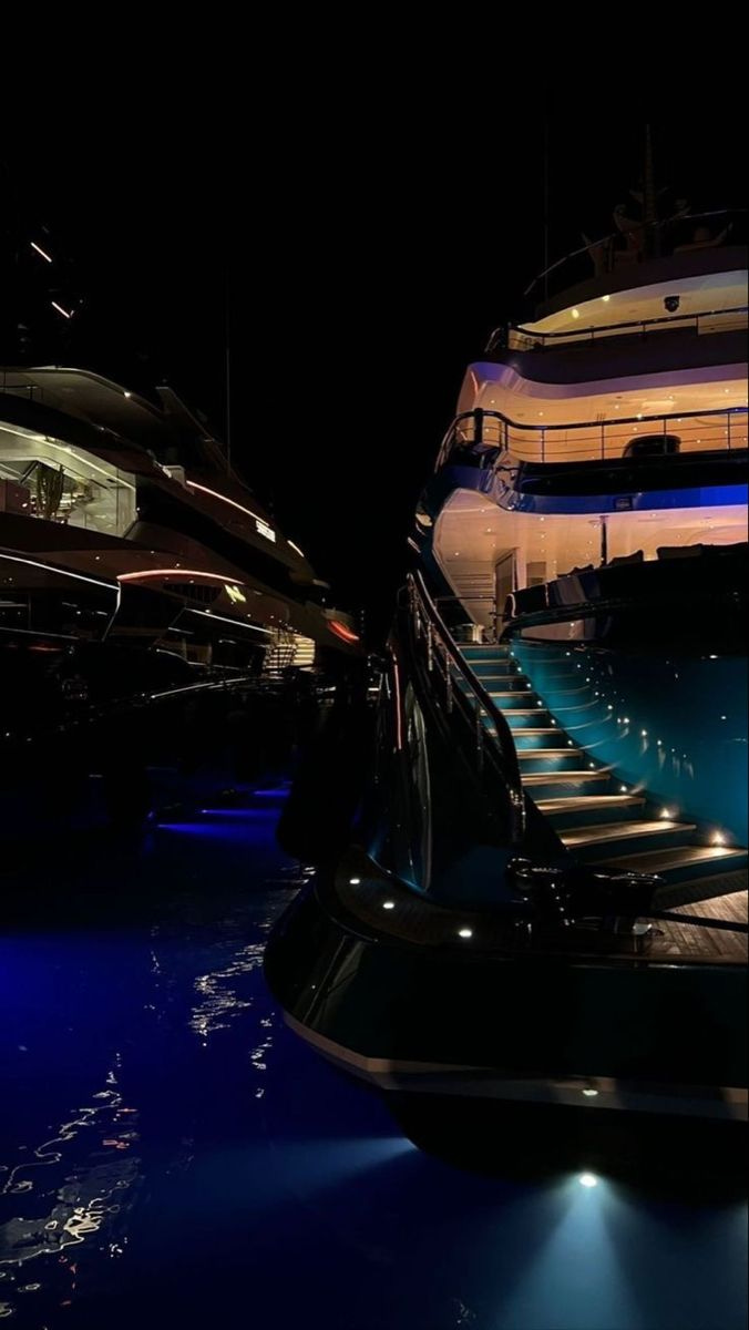 This may contain: the stairs are lit up at night in front of a boat that is floating on water