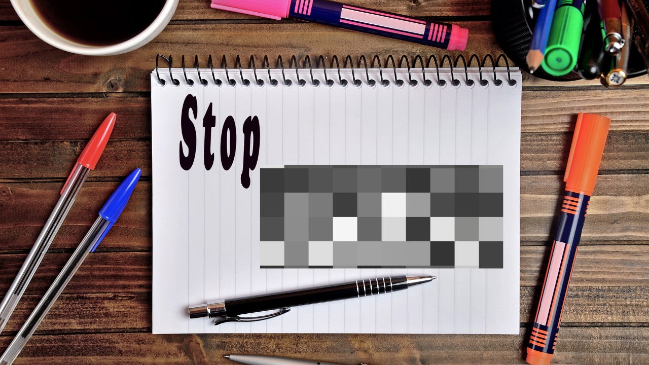 A notebook surrounding by pens, with the word "Stop" written next to a pixelated word.