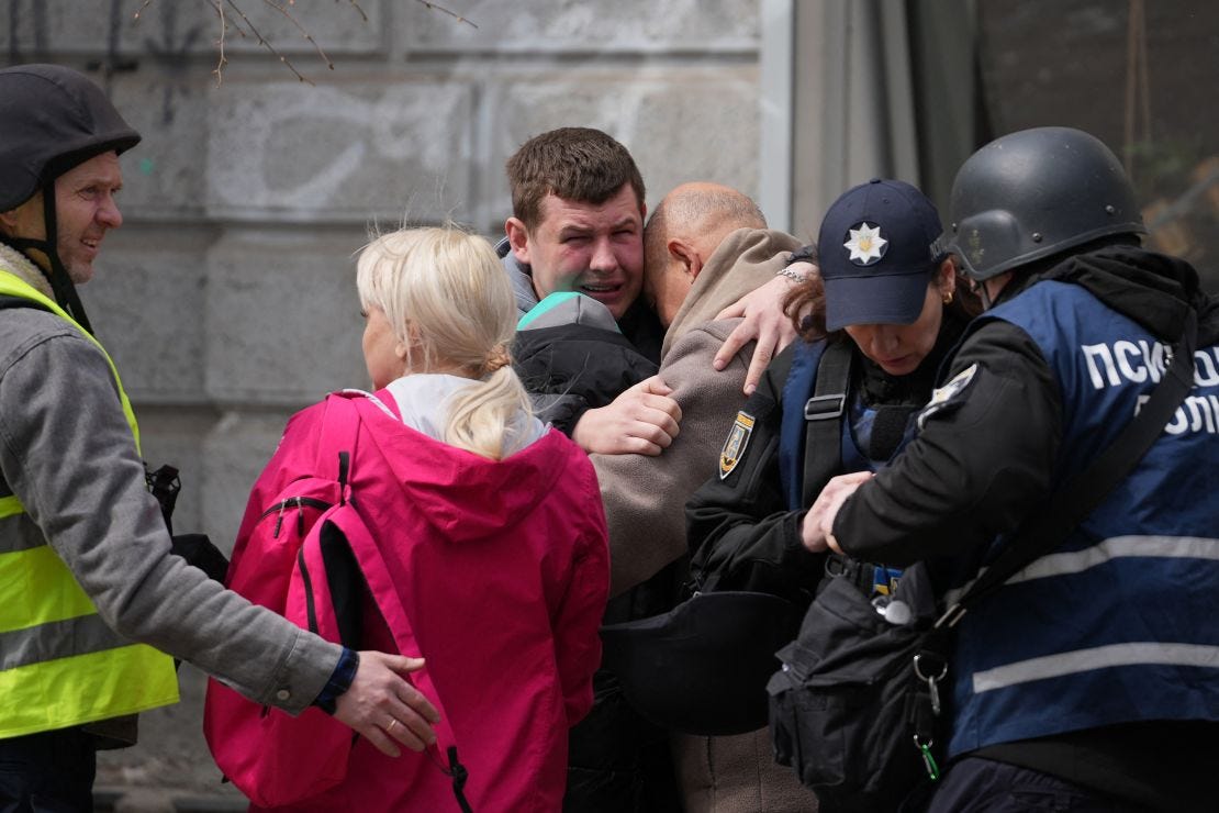 Two men comfort each other as Ukrainian police psychologists provide assistance to local residents.