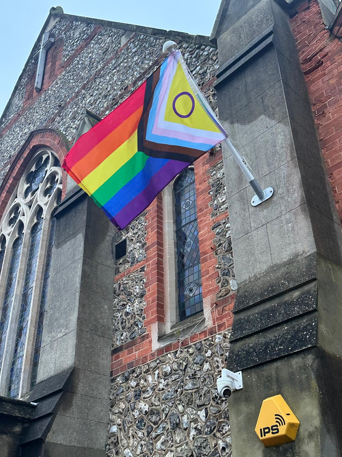 progress pride flag flies outside a church