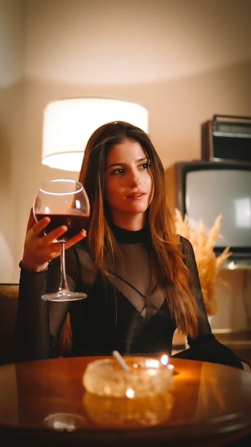 Free A Woman in Black Long Sleeve Shirt Holding a Clear Wine Glass Stock Photo
