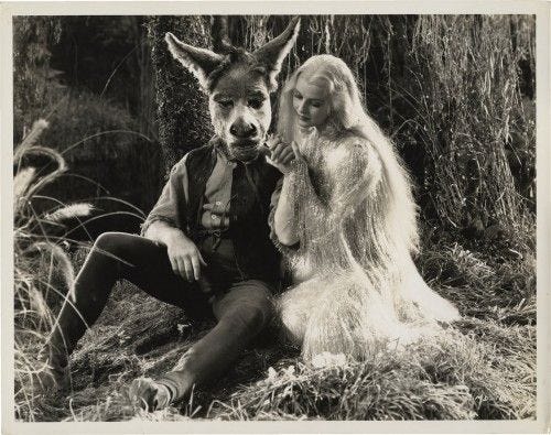 This may contain: a man and woman sitting next to each other in front of a forest with a wolf mask on