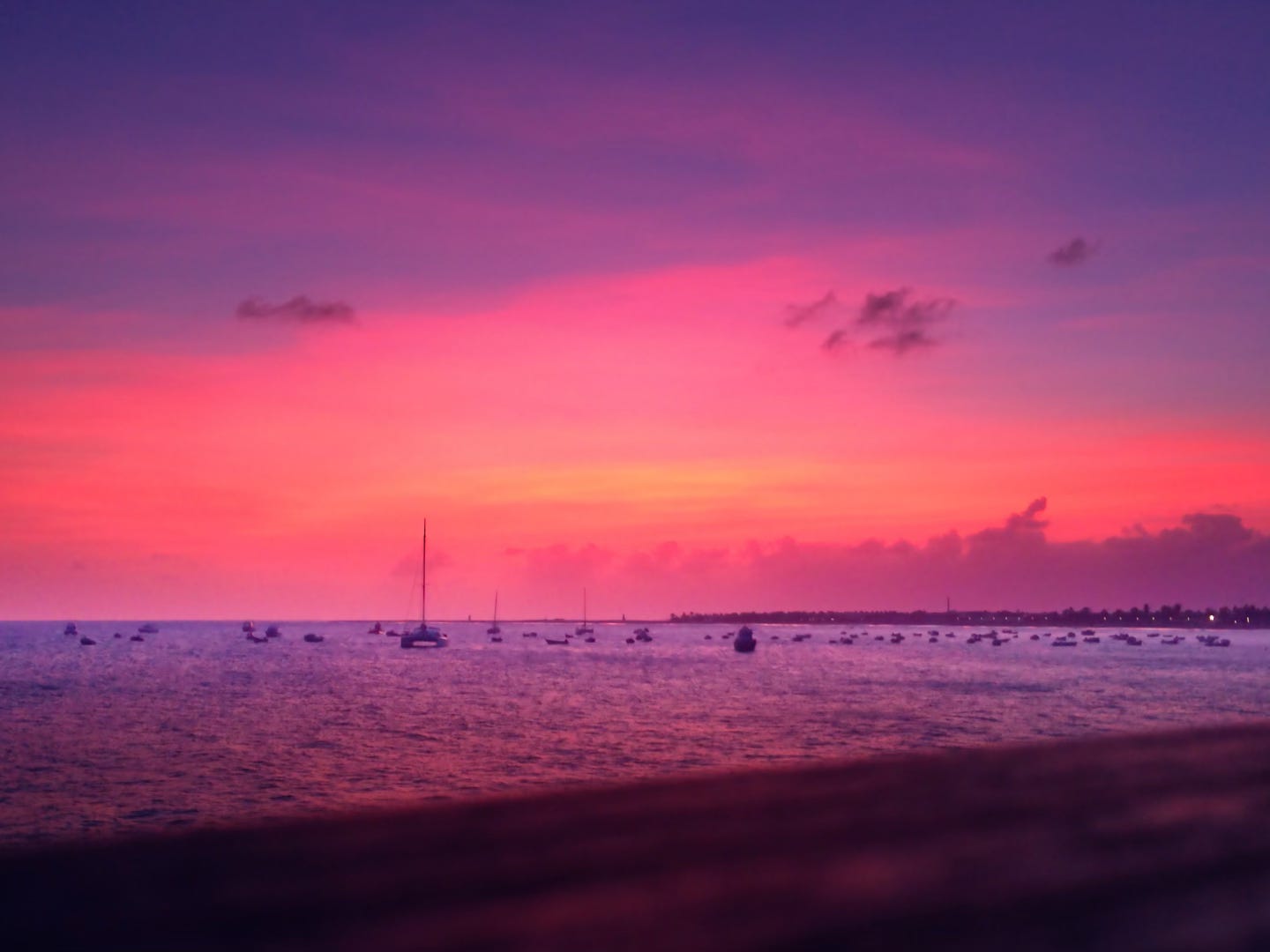 Silhouettes of boats on calm waters under a vibrant pink and purple sunset, symbolizing a peaceful moment of reflection and self-reclamation.