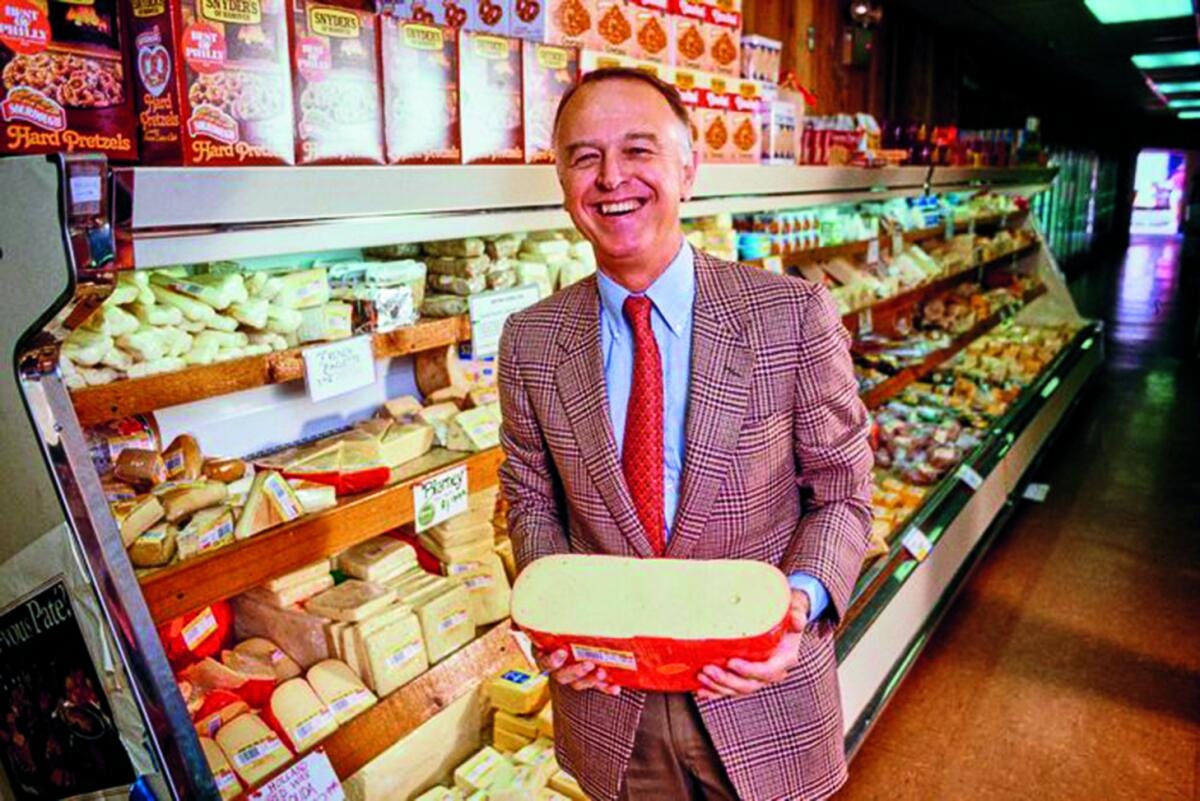 Joe Coulombe displays a wheel of cheese. 