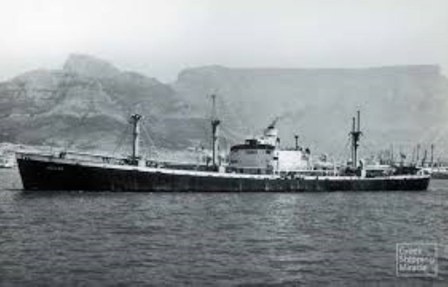 Greek freighter 1945 in the sea with mountains behind