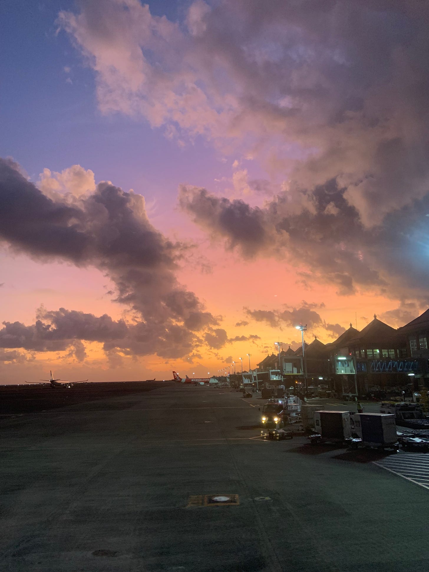 Orange, purple, and blue sunset over clouds at Bali's international airport