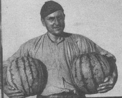 Black and white photo of a man holding two watermelons, one under each arm