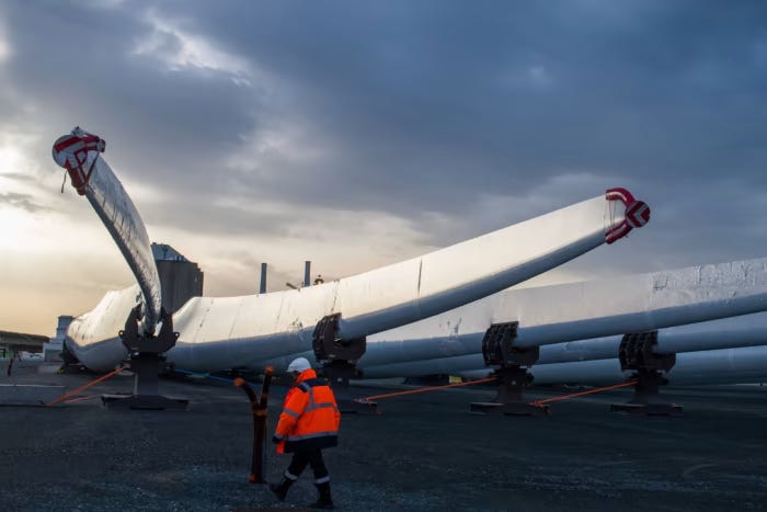 A worker passes wind turbine blades at the Siemens Gamesa Renewable Energy plant at the Port of Le Havre in Le Havre, France