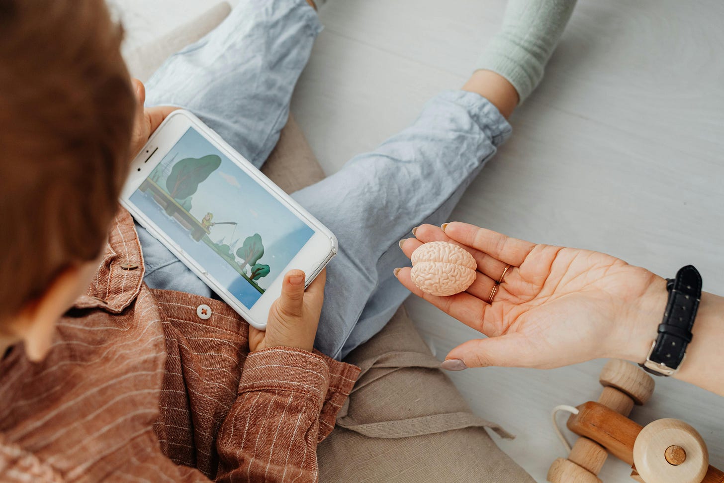 A Person's Hand Near a Kid Holding a Smartphone