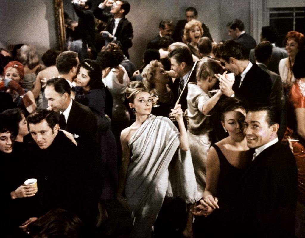 An image from Breakfast at Tiffany's of Holly, standing in the middle of a party scene and looking out at the camera