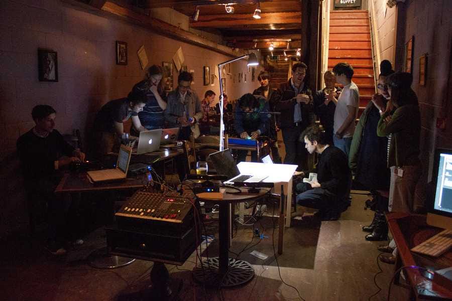 Early sharing of Cave of Sounds. The members of Cave of Sounds are grouped around various laptops and electronics, with other members of Music Hackspace seeing what's going on. Photo by Tim Murray-Browne