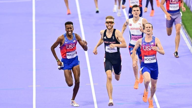 A field of sprinters is seen approaching the finish line in a race.