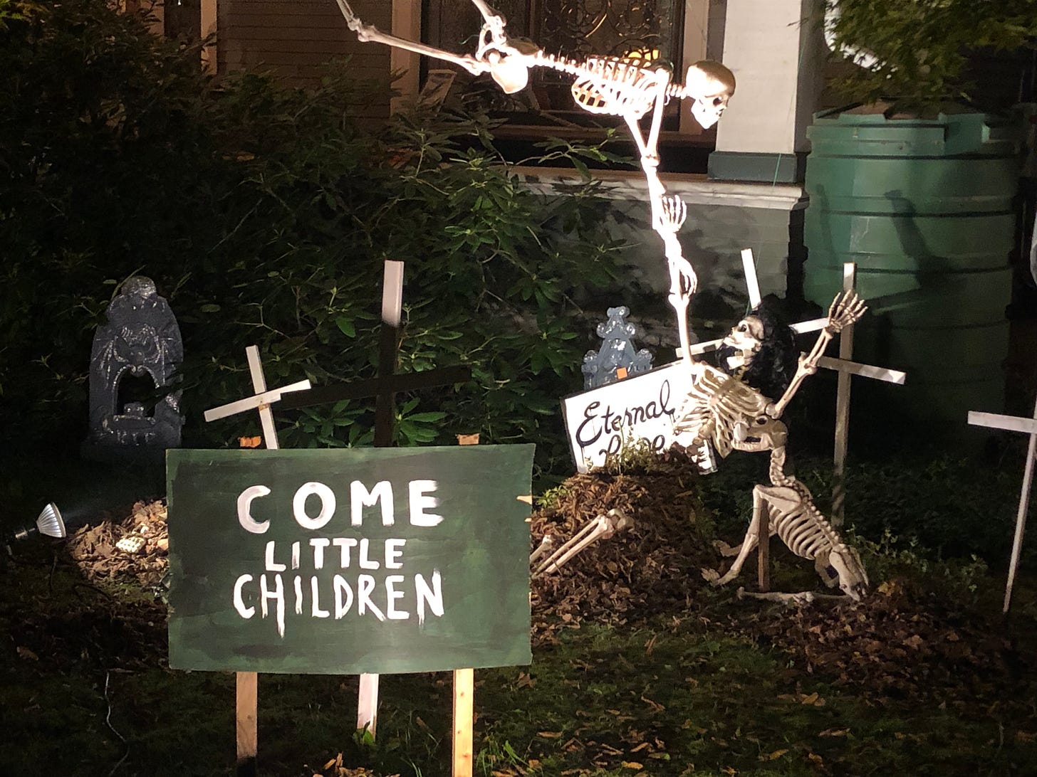 two skeletons in a graveyard with a sign that says "come little children"