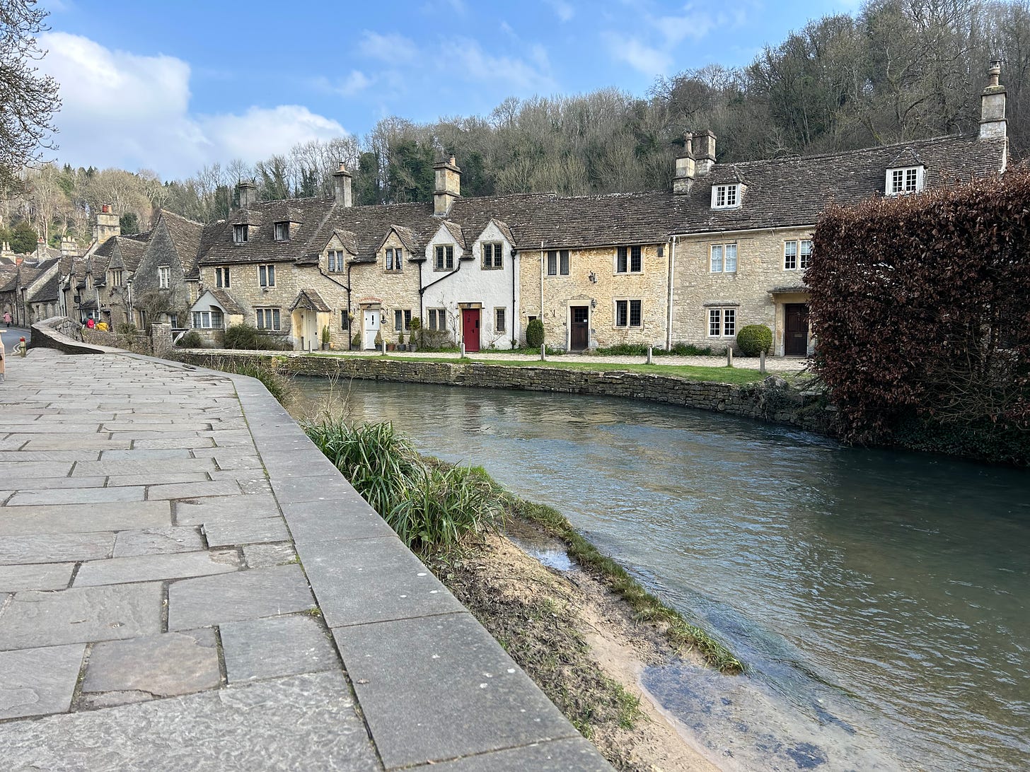The Bybrook River flowing in front of a row of ancient stone cottages at Castle Combe, Wiltshire Image: Roland's Travels