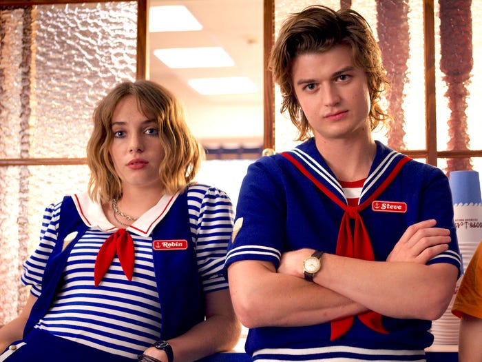 Robin and Steve from Stranger Things season 3 looking to camera while wearing their Scoops Ahoy uniforms.