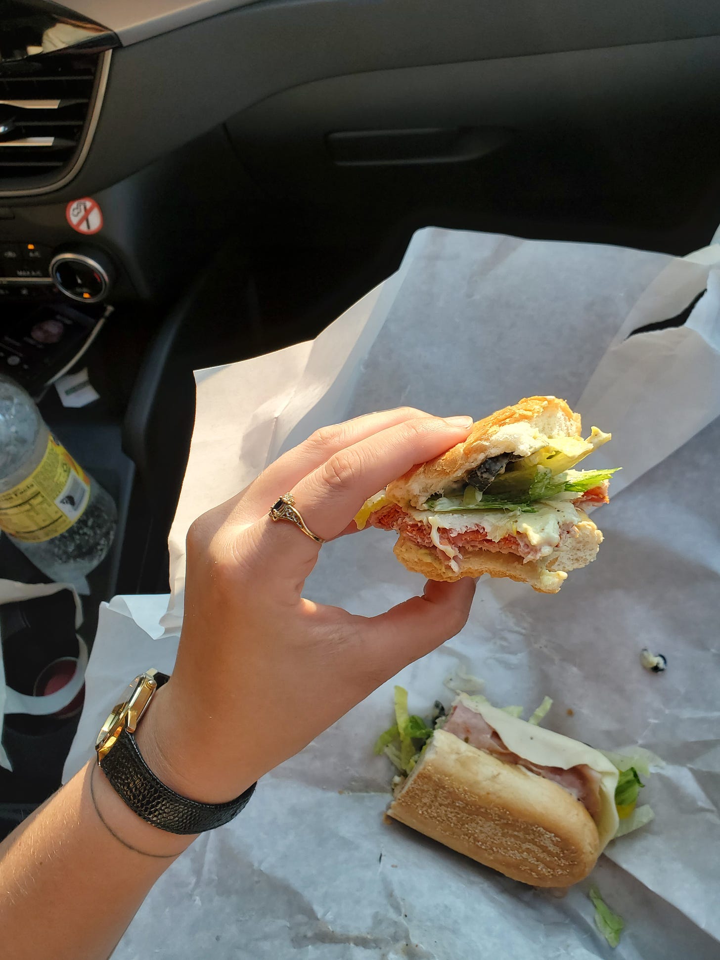 The final bites of a magnificent sandwich, held aloft in a passenger seat. 