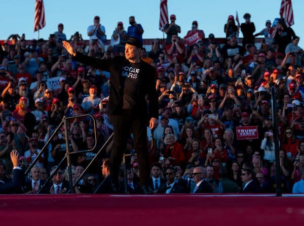 Elon Musk waves to a crowd at a Trump rally.