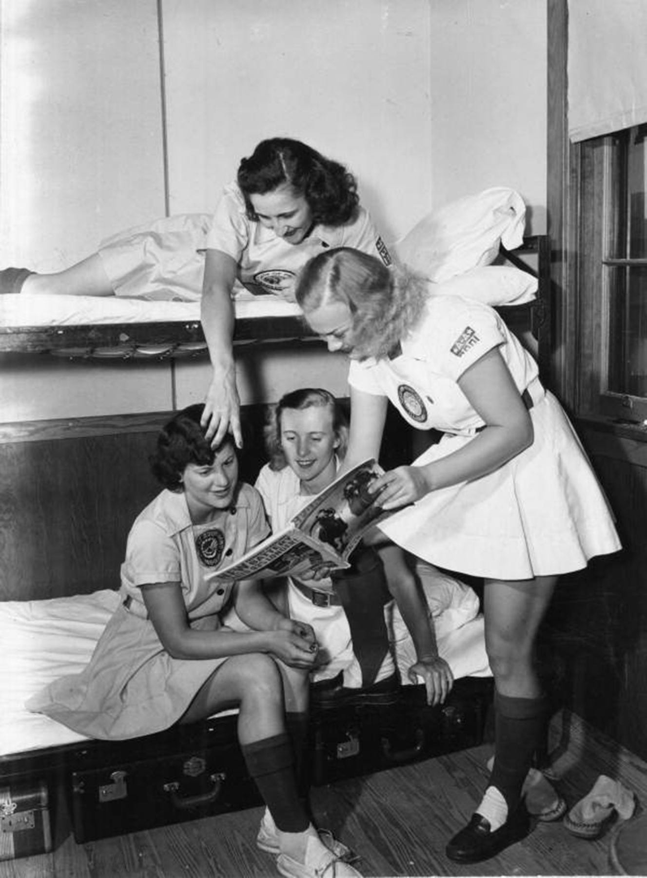 A.A.G.P.B.L. players (left to right) Daisy Junor, 27, South Bend; Dorice Reid, 19, Chicago club member; Dodie Healy, 19, Chicago club member; (top) Gene George, 20, Peoria club member, fraternizing in a bunk room over a sports magazine, 1948. (Photo courtesy State Archives of Florida)