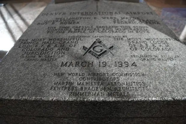 A stone plaque inscribed with a freemasons logo, the date March 19 1984, and various phrases and credits including "New World Airport Commission"