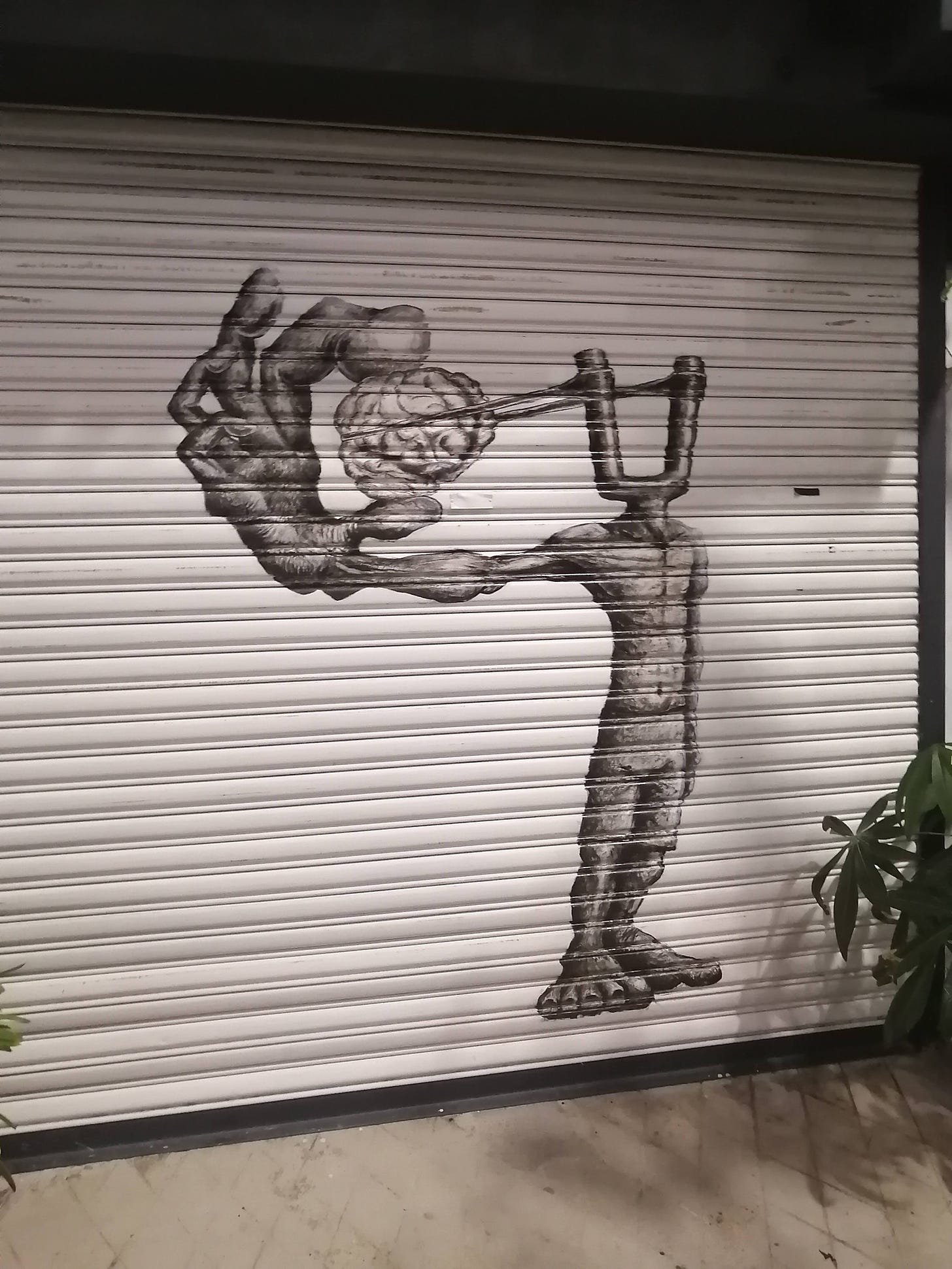Graffiti of a man. His head is a catapult, and he is pulling his brain with his own hand in the rubber band of the catapult.