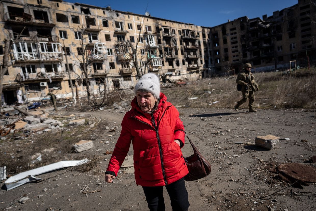 Uma senhora idosa é vista em frente a um prédio danificado na cidade de Vuhledar, na linha de frente, enquanto a guerra entre a Rússia e a Ucrânia continua em Donetsk