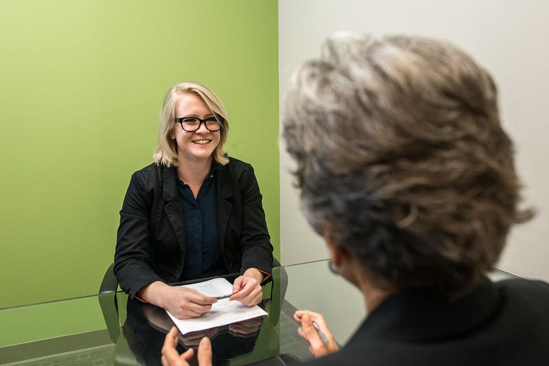 A woman being interviewed for a job from a perspective over the shoulder of the interviewer.