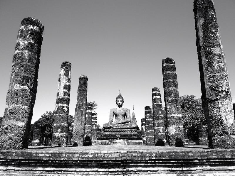 black and white photo of a Buddha statue in the ruins of an ancient temple