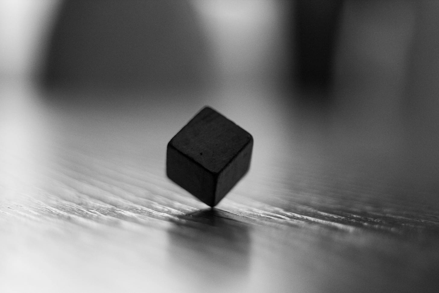  black cube sitting on top of a wooden table photo