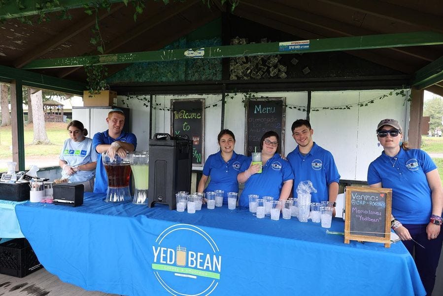 campers staff a table with cups of ice and coffee. They wear matching blue polo shirts.