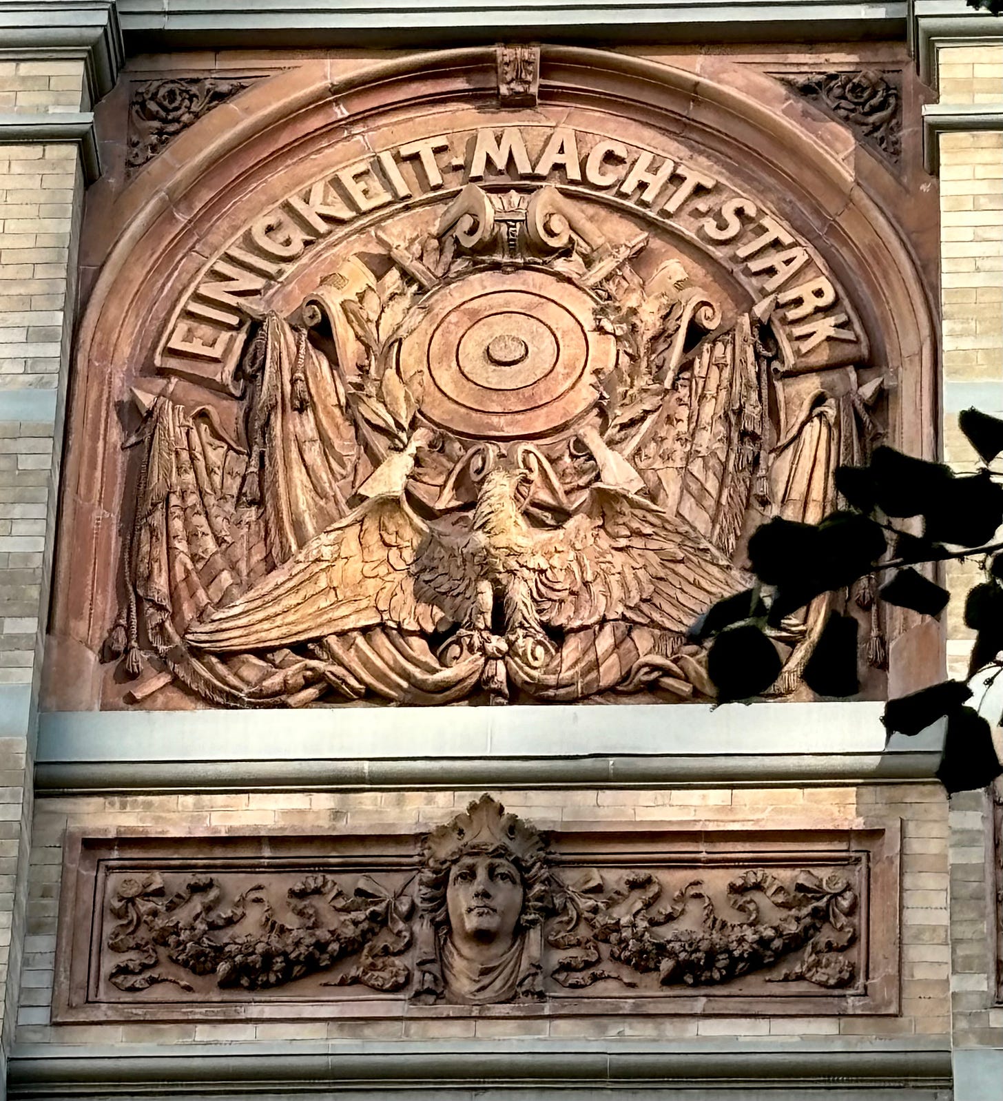 A detail of a carving on Village Works. There is a target over an eagle. It reads Einigkeit-Macht Stark.