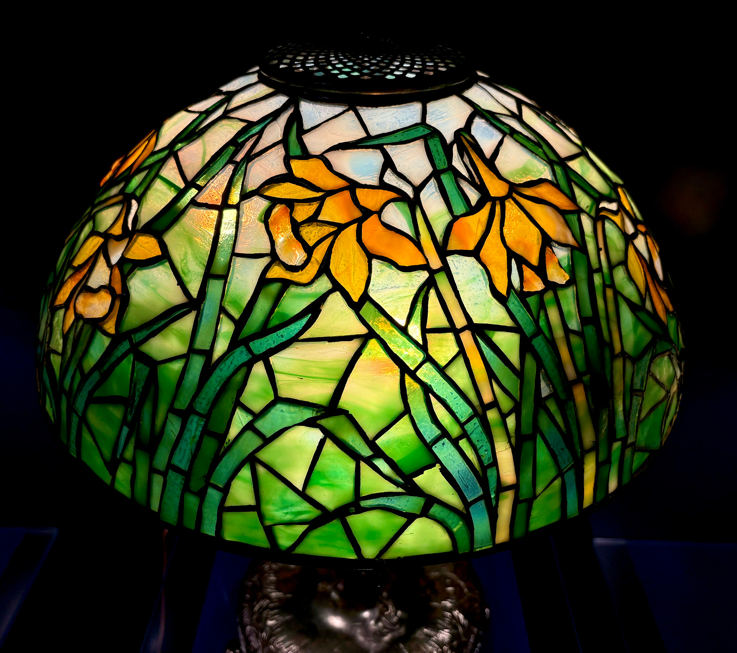 A closer view of the daffodil lamp, the yellow daffodils against pale glass bluer towards the top like sky.