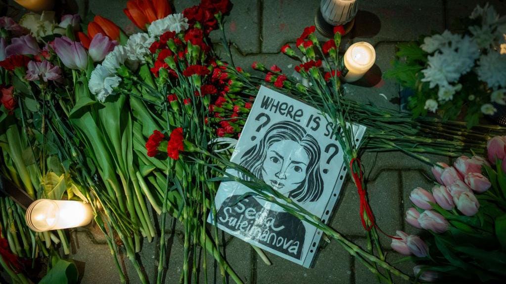 A sign with a graphic repressentation of the 26 year old Seda Suleymanova, at a makeshift shrine with candles at the Russian embassy in Warsaw, Poland