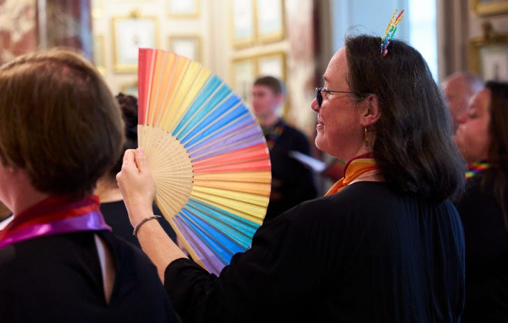 A woman holding a rainbow fan in a crowd