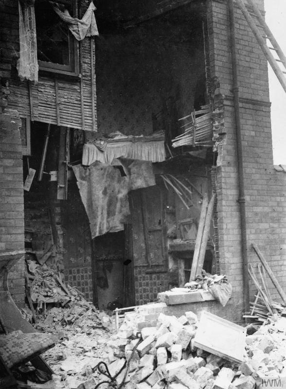 A house with its front blown in and a pile of rubble outside. For Bairnsfather enthusiasts, it looks like damage caused by "Mice".