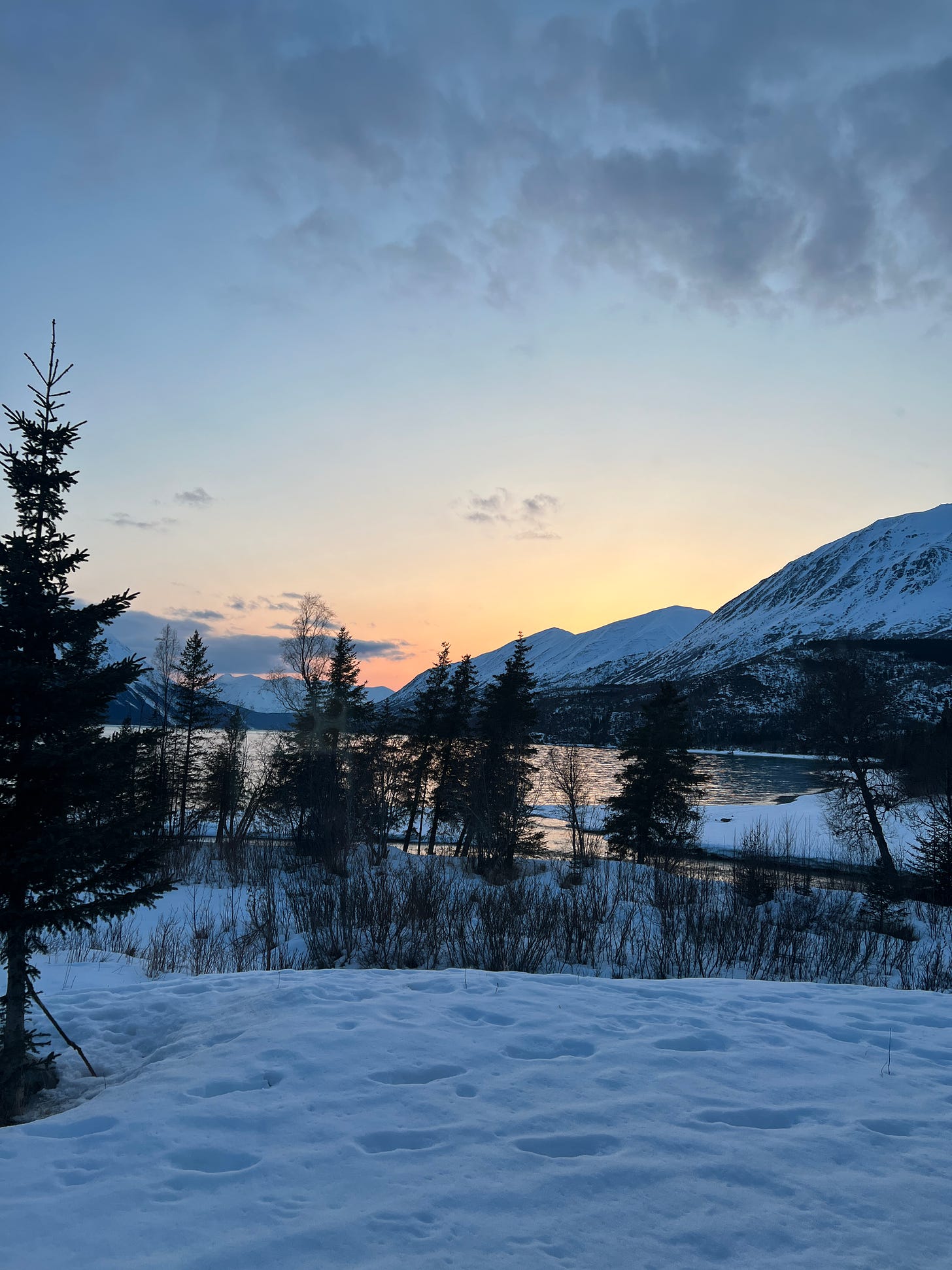 A beautiful snowy sunset over a lake in Alaska. The author would like it to hurry up and get dark and make with the Northern Lights already.
