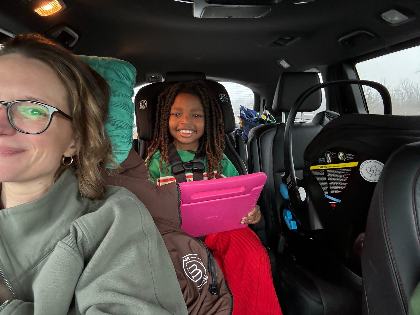 a white woman and black girl in a car, smiling at the camera