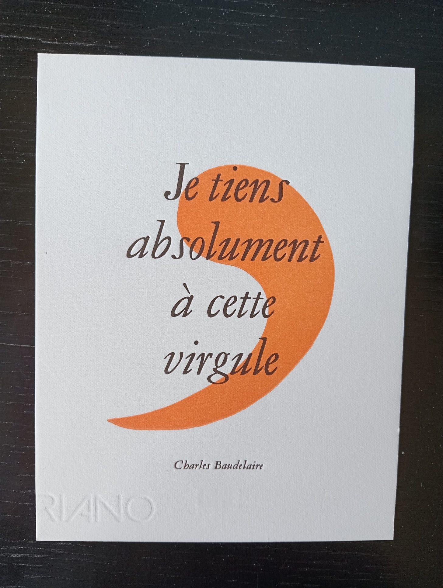 White postcard with large orange comma overlaid with the words "Je tiens absolument à cette virgule"