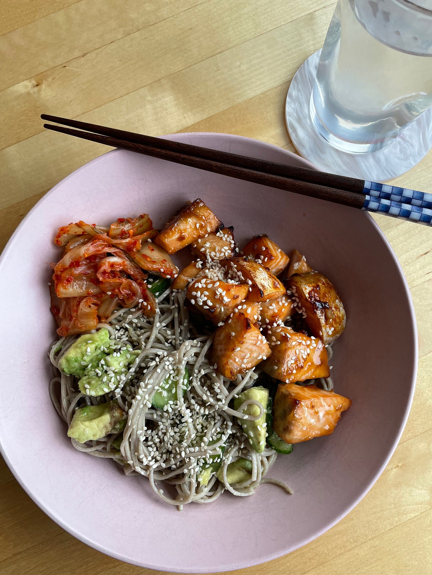 Bowl of soba noodles with avocado and cucumber with doenjang roasted salmon and kimchi.