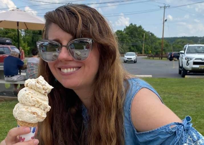 A picture of Alissa Grosso holding a salted caramel ice cream cone at an outdoor ice cream stand.