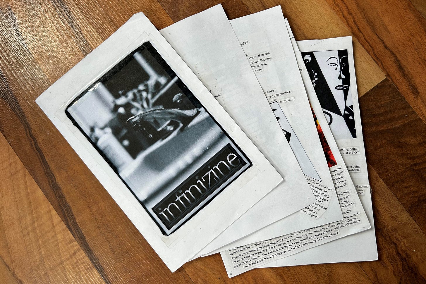 A half-page booklet has been arranged with its leaves fanned out like a hand of playing cards. Peeking out from the edges of each page can be seen type-written cut-out text that has been arranged in a collage, with some high-contrast but unidentifiable imagery. The cover of the booklet features the word "infinizine" in lower-case faux-metallic text below a dramatic black and white photo of a dripping faucet. The cover photo has been attached to the booklet with scotch tape.