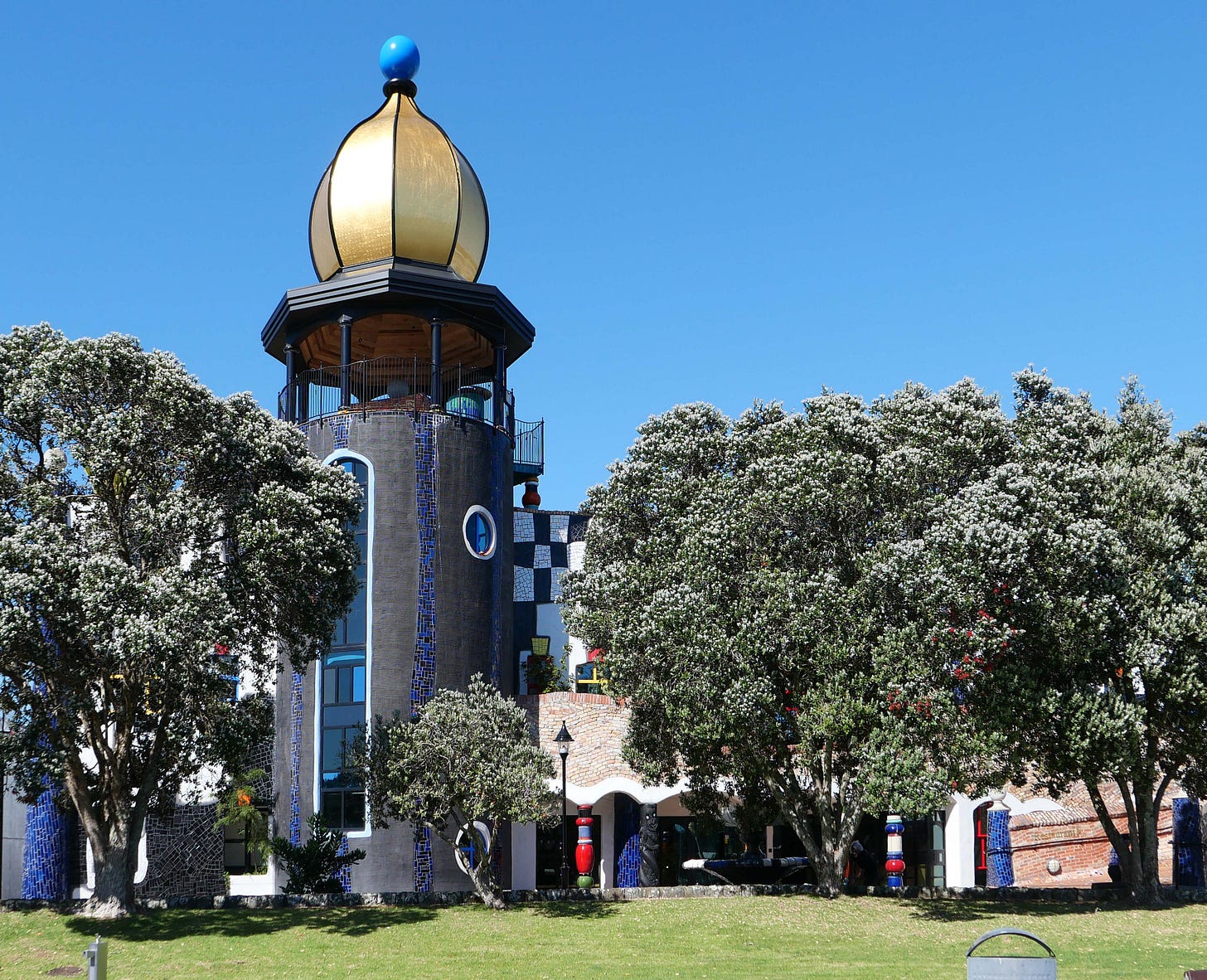 The tower and gold-covered dome of the Hundertwasser building in Whangarei, under a clear blue sky.