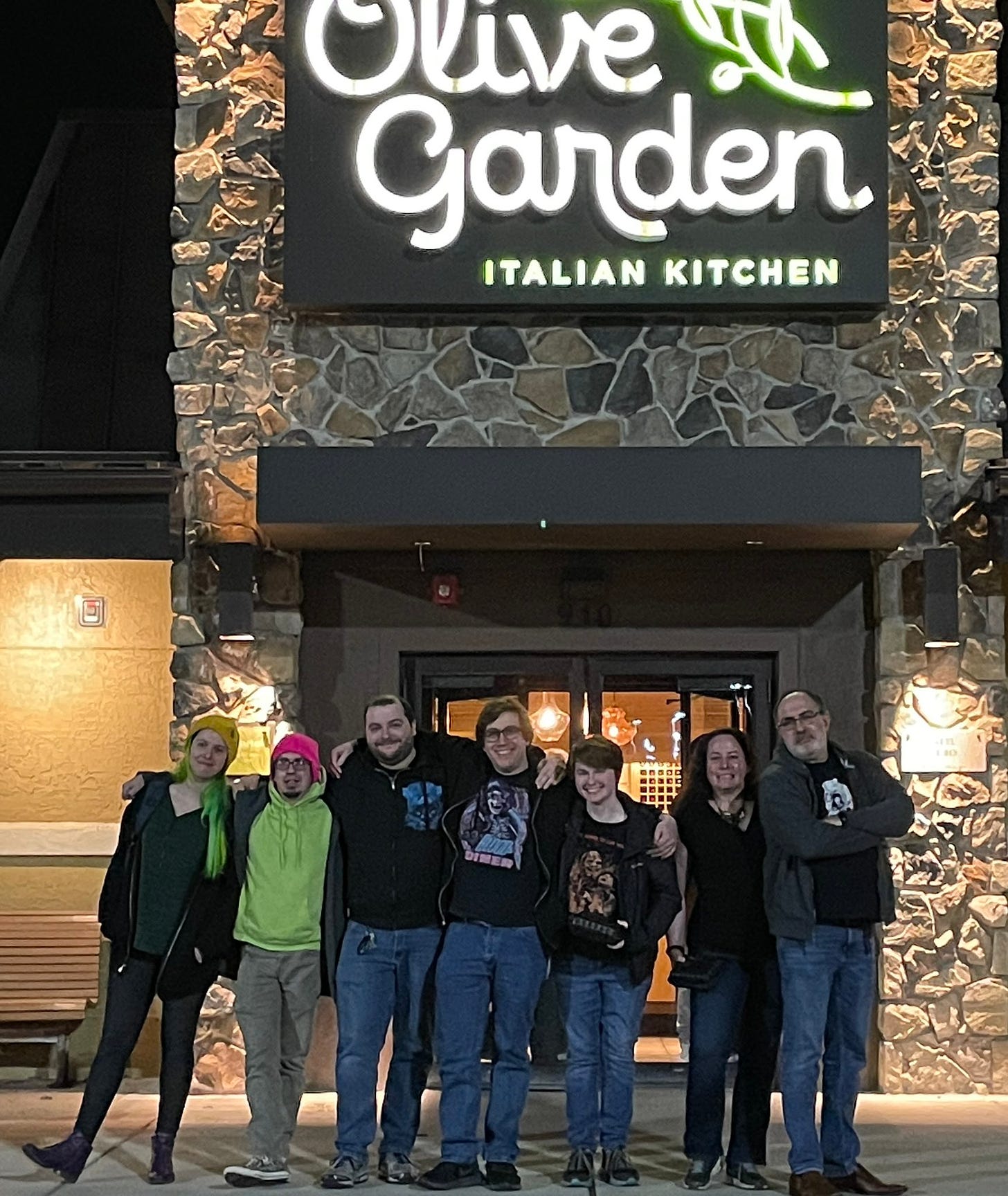 A group of authors standing in front of an Olive Garden restaurant.