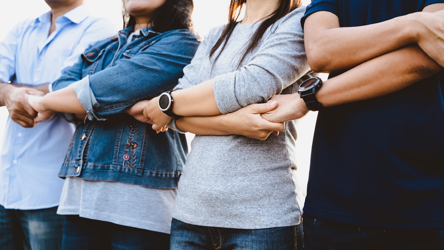 Women and men with joined hands standing together side by side