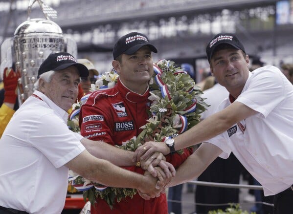 FILE - Car owner Roger Penske, left, and Tim Cindric, right, president of Penske Racing, clasp hands with Indianapolis 500 winner Gil de Ferran, of Brazil, on May 25, 2003, in Indianapolis. De Ferran, winner of the 2003 Indy 500 and holder of the closed-course land speed record, died Friday, Dec. 29, 2023, while racing with his son at The Concourse Club in Florida, multiple former colleagues confirmed to The Associated Press. He was 56. (AP Photo/Tom Strattman, File)