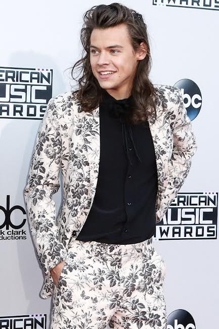 Harry Styles in a black and white Gucci floral suit with a black button-up underneath. This was his long hair era.