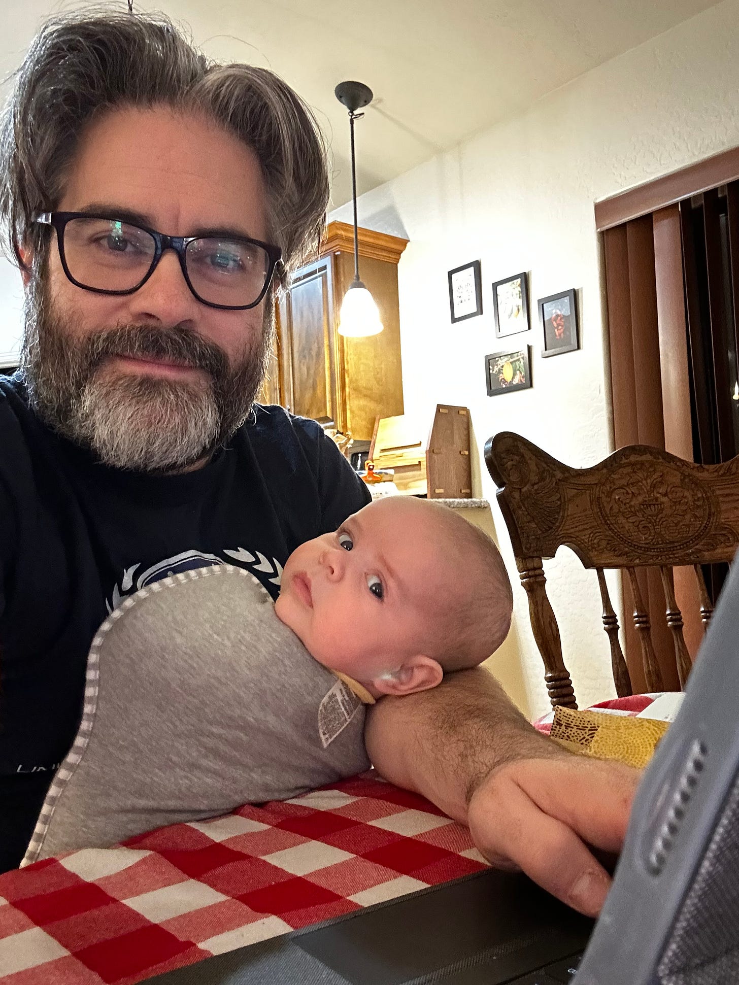 A photograph of me using my tablet while holding a baby, who is looking at the camera.